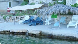 A poolside area with lounge chairs and a thatched umbrella. - A2 - apt Near Beach With Terrace and the sea View (Blato)