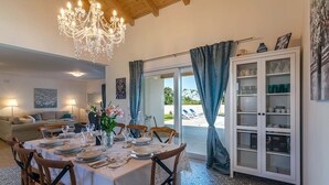 Comedor con candelabro, una mesa dispuesta para cuatro comensales y vista al exterior.