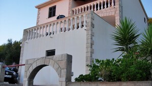 A building with a stone facade, a balcony with balustrades, and a small window.