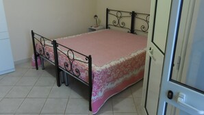 Ein Schlafzimmer mit einem Bett, einem Nachttisch, einem kleinen Tisch und einer Tür.