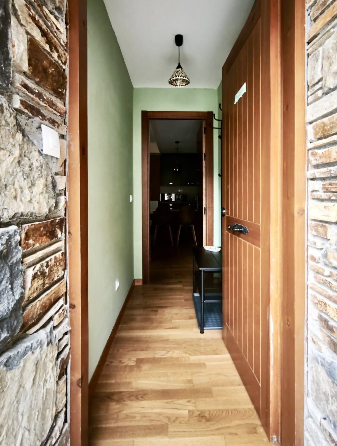 Ein Flur mit Holzboden, einer Steinwand und einer Holztür.