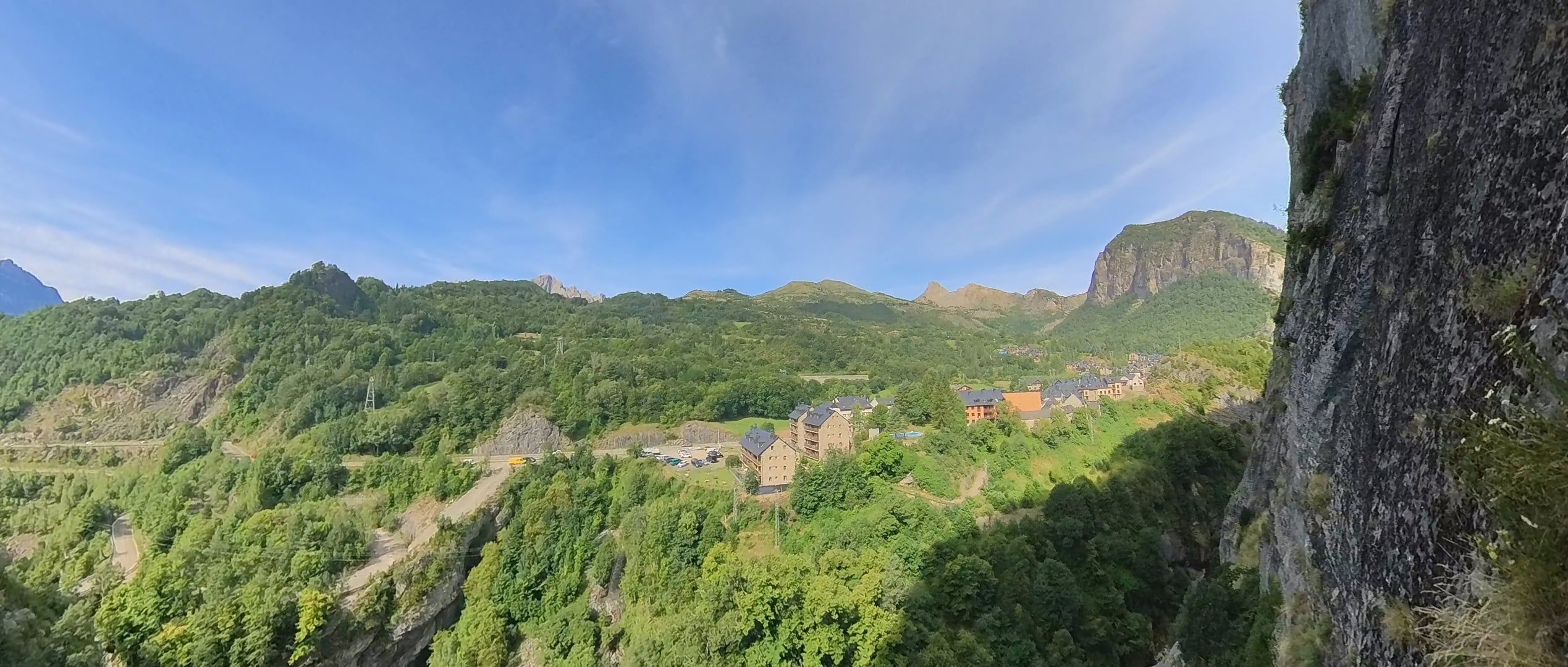 A mountainous landscape with a building complex surrounded by dense forest.