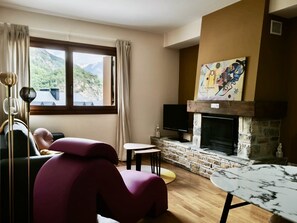 Ein Wohnzimmer mit Kamin, einer Couch, einem Fernseher und einem Bild an der Wand.