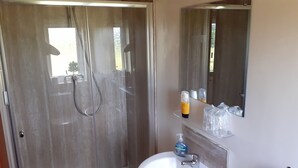Ein Badezimmer mit Dusche, Waschbecken und Spiegel.