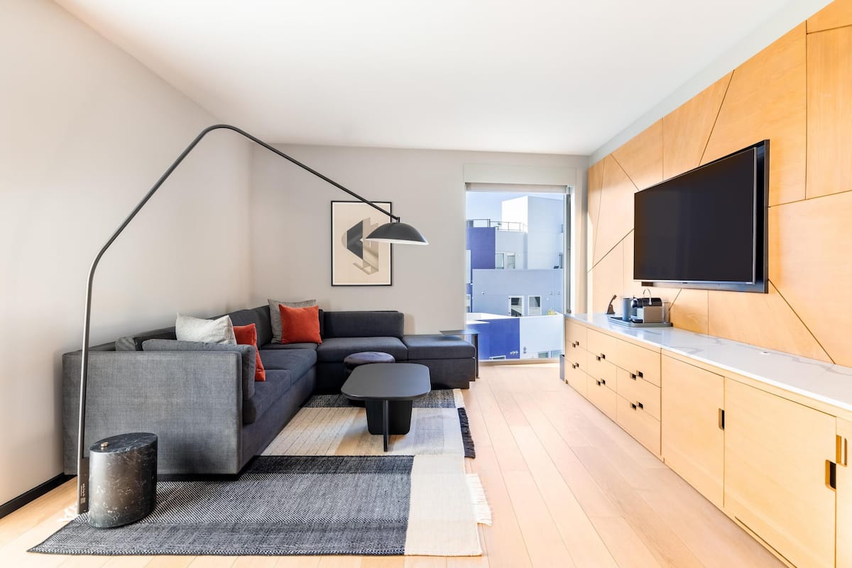 A modern living room with a sofa, coffee table, and a TV mounted on a wooden cabinet.
