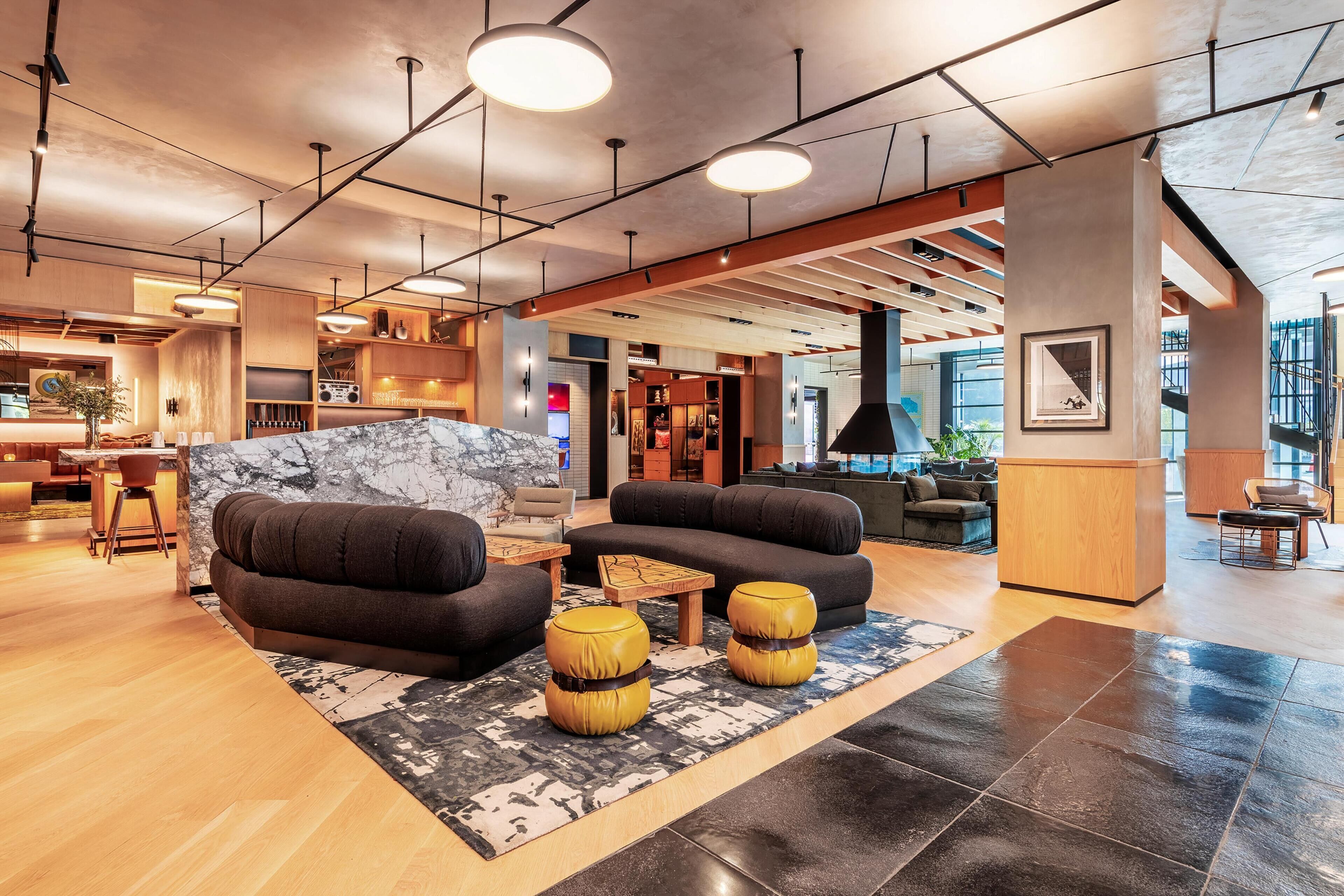 A modern lobby with a sofa, ottomans, a marble accent wall, and a reception desk.