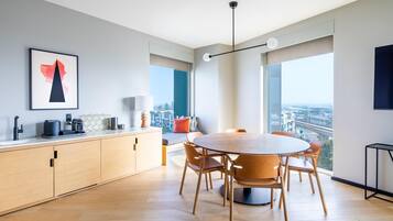 A modern kitchen with a dining area, large windows, and a city view.