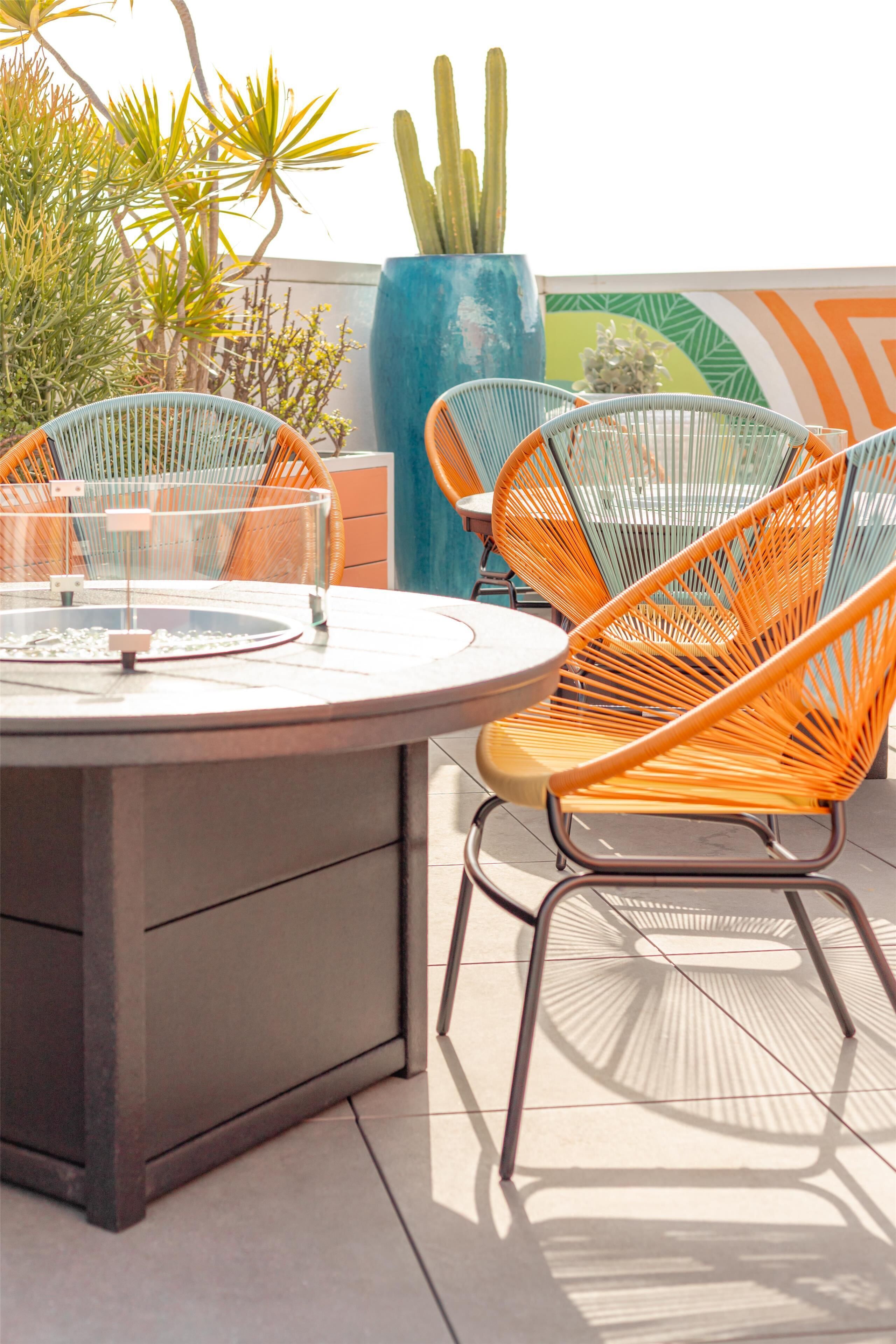 A round table with chairs, a large blue planter, and various plants.