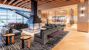A modern lounge area with a fireplace, sofas, and a staircase. - The Shay Hotel (Culver City)