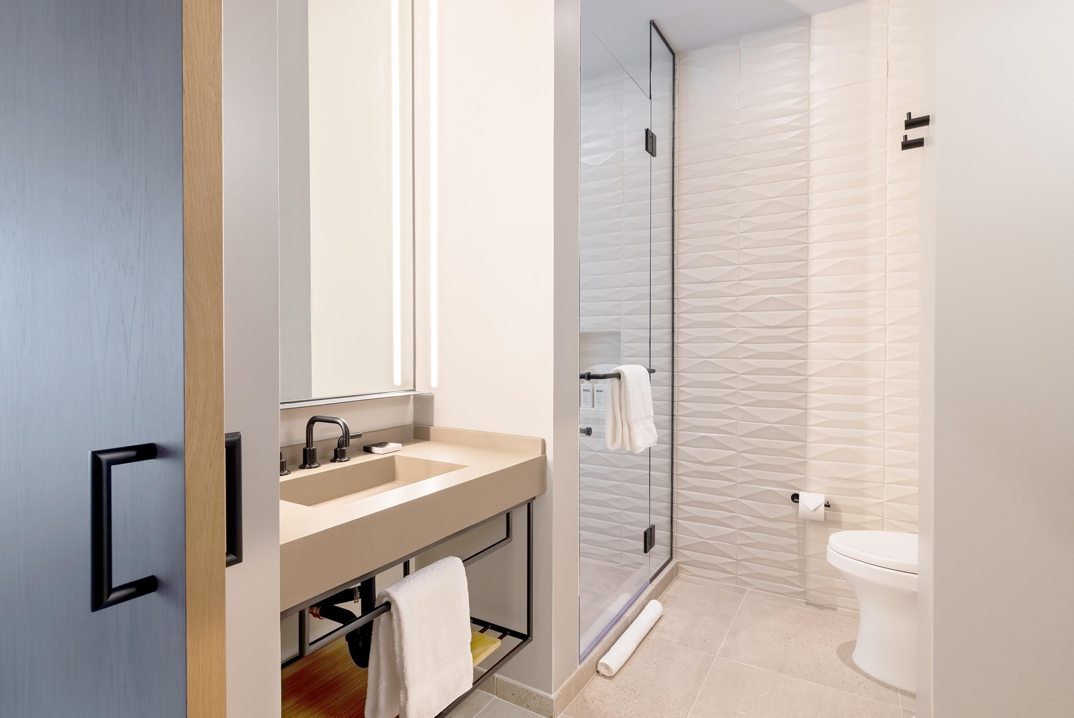 A modern bathroom with a sink, mirror, and toilet.