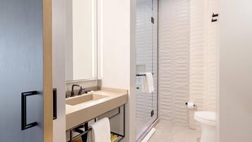 A modern bathroom with a sink, mirror, and toilet.