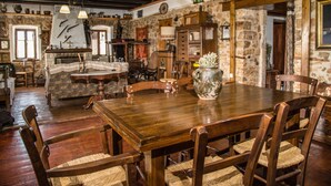 Un comedor rústico con una mesa y sillas de madera, rodeado de paredes de piedra y vigas de madera.