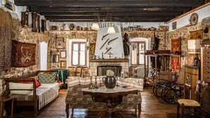Una habitación rústica con pared de piedra, muebles de madera, chimenea y varios objetos decorativos.