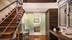 Una cocina moderna con escalera de madera, un comedor con una silla y vistas al baño.
