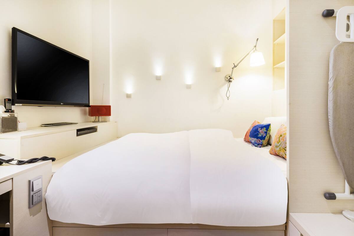 Une chambre d’hôtel équipée d’un lit, d’une télévision, d’un bureau et d’une armoire.