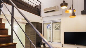 Un interior moderno con una escalera de madera, un televisor de pantalla plana y un sillón acolchado.