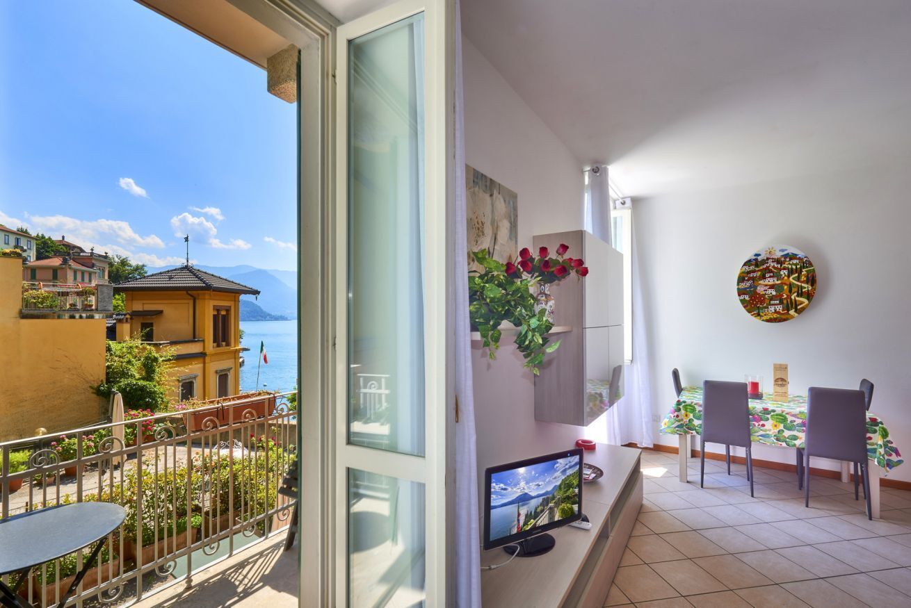 A balcony with a table and chairs, a TV, and a view of the sea.