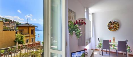 A balcony with a table and chairs, a TV, and a view of the sea.