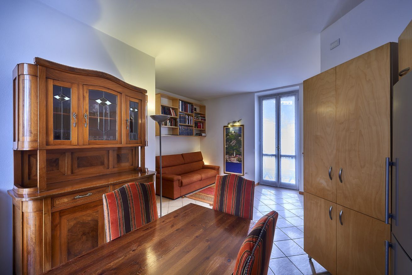 Un comedor con mesa y sillas de madera, un sofá y un mueble con puertas de vidrio.