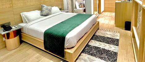Una habitación de hotel moderna con una cama grande, una mesita de noche, un espejo y un armario de madera.