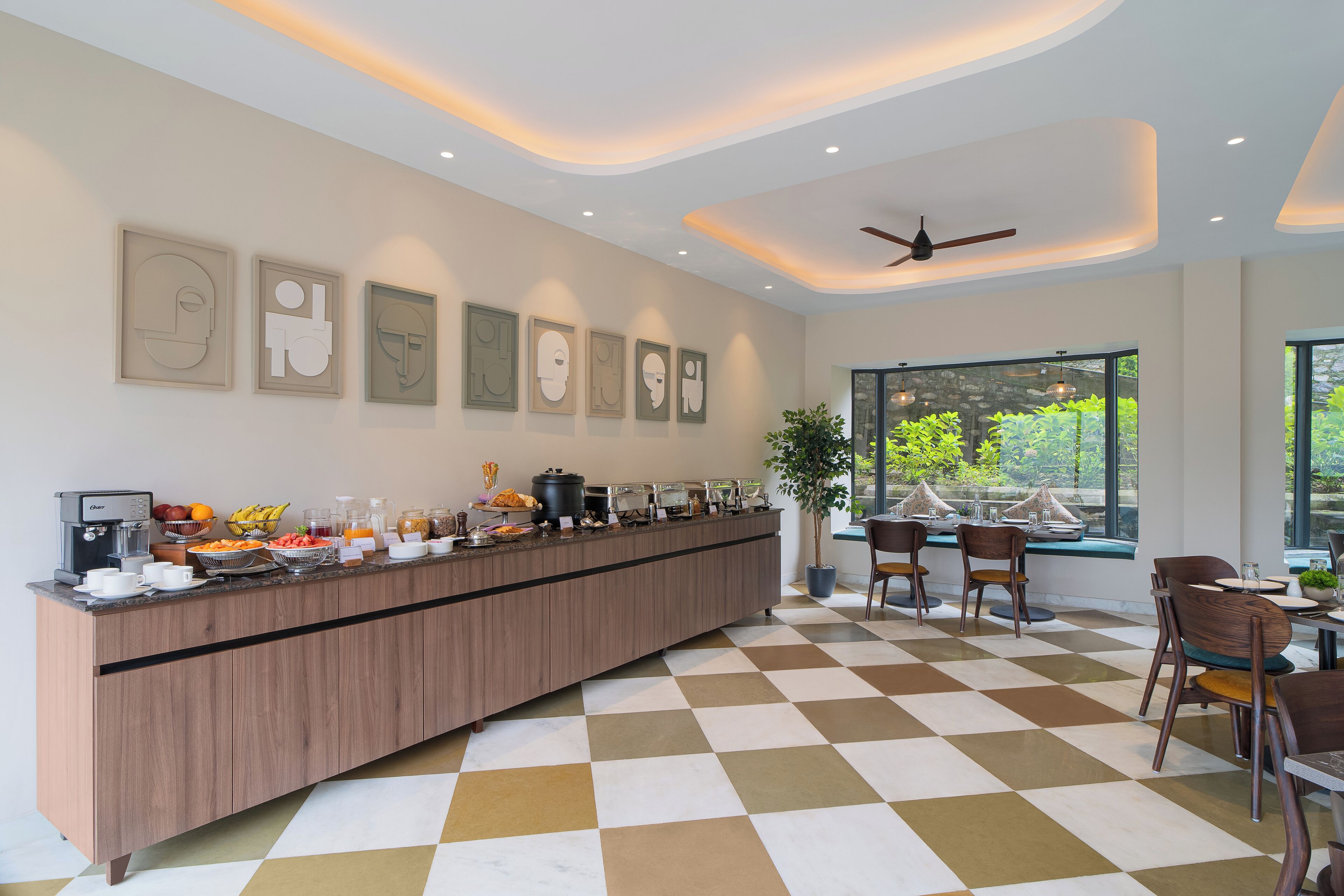Un comptoir de petit-déjeuner moderne, avec un sol à carreaux, un ventilateur de plafond et des œuvres d’art encadrées accrochées au mur.