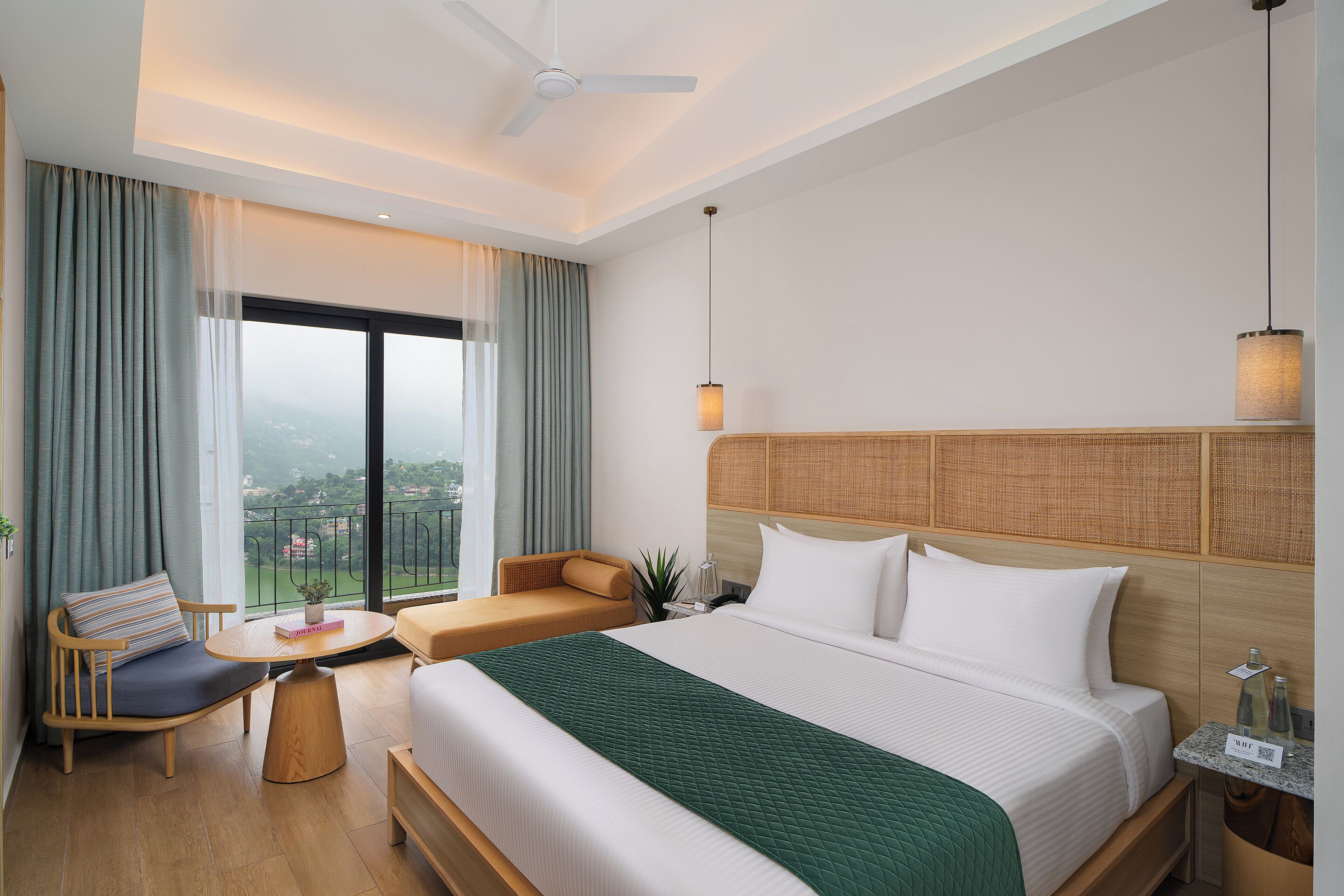 A hotel room with a large bed, a sofa, a small table, and a view of the city.