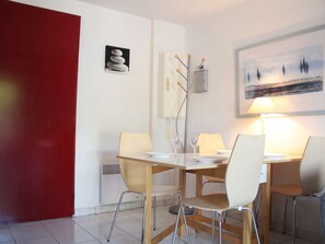 A dining area with a table, chairs, and a lamp. There are artworks on the walls.