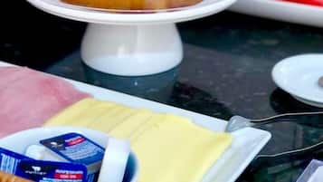 Una presentación de postres con un pastel sobre un pedestal, un plato con pastel en porciones, y un bol con un paquete azul.