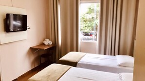 A hotel room with two beds, a desk, a TV, and a window with curtains. - Hotel Belvedere Araras - Fácil Acesso Hospital São Leopoldo e Faculdades (Araras)