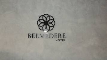 Un logotipo con el texto "BELVEDERE HOTEL" sobre una pared texturizada.