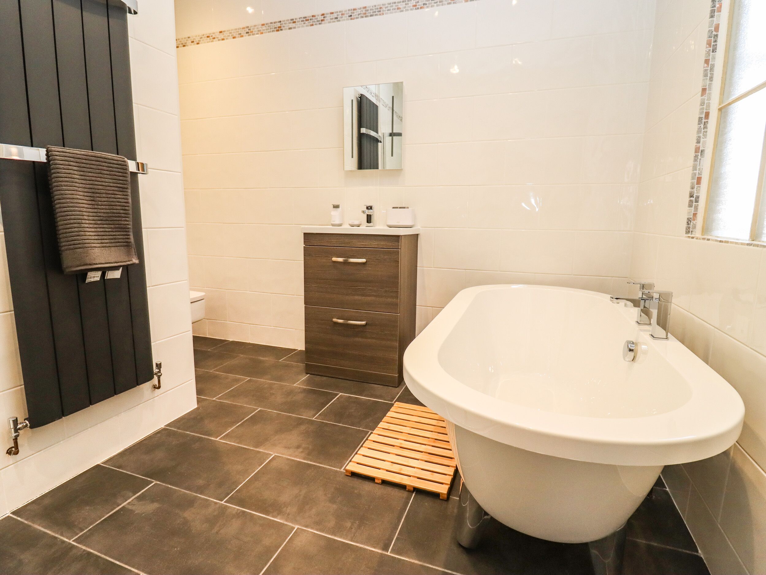Une salle de bain moderne avec une baignoire sur pieds, un meuble-lavabo avec un miroir et un porte-serviettes.