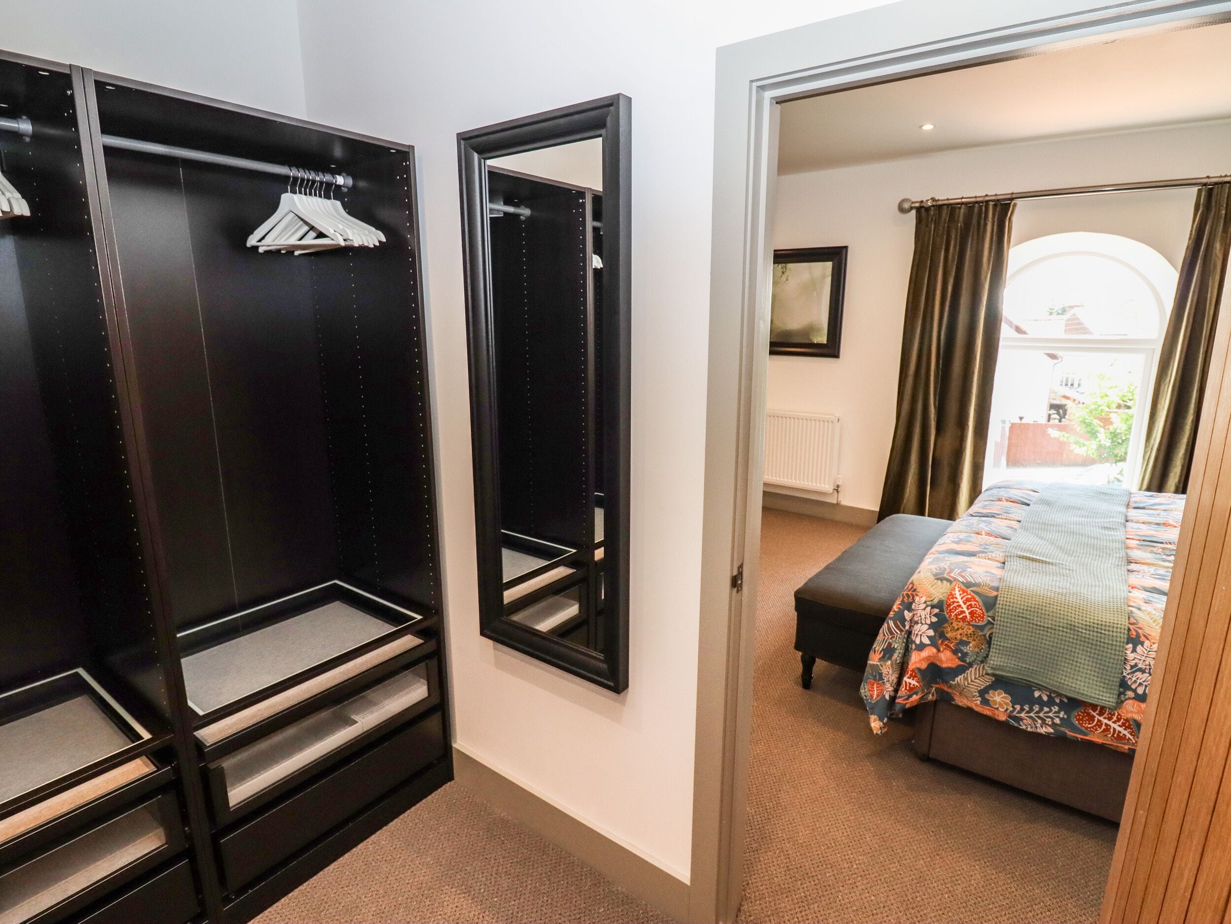 A bedroom with a bed, a wardrobe, and a mirror.