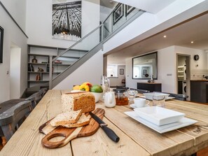 Eine moderne Küche mit einem Holztisch, einem Schneidebrett mit Brot und einem Wasserkocher.