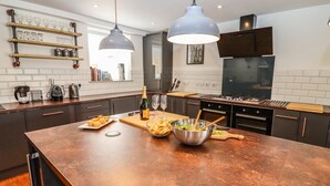 Una cocina moderna con una isla grande, luces colgantes y una variedad de electrodomésticos.