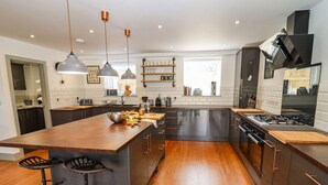 Una cocina moderna con una isla grande, armarios oscuros y electrodomésticos de acero inoxidable.