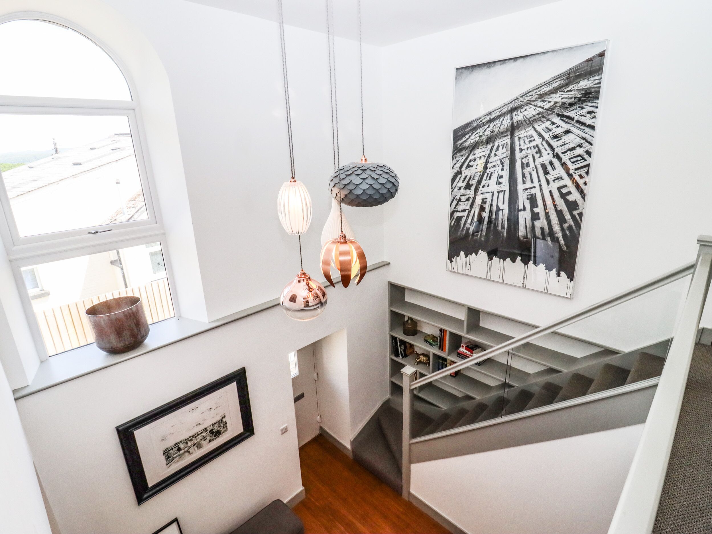 A staircase with a metal railing, a framed picture on the wall, and a window with a view of the outside.