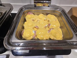 Disposição de buffet com um recipiente de aço inoxidável contendo alimentos.