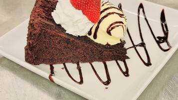 A slice of chocolate cake with whipped cream and a strawberry on a white plate.