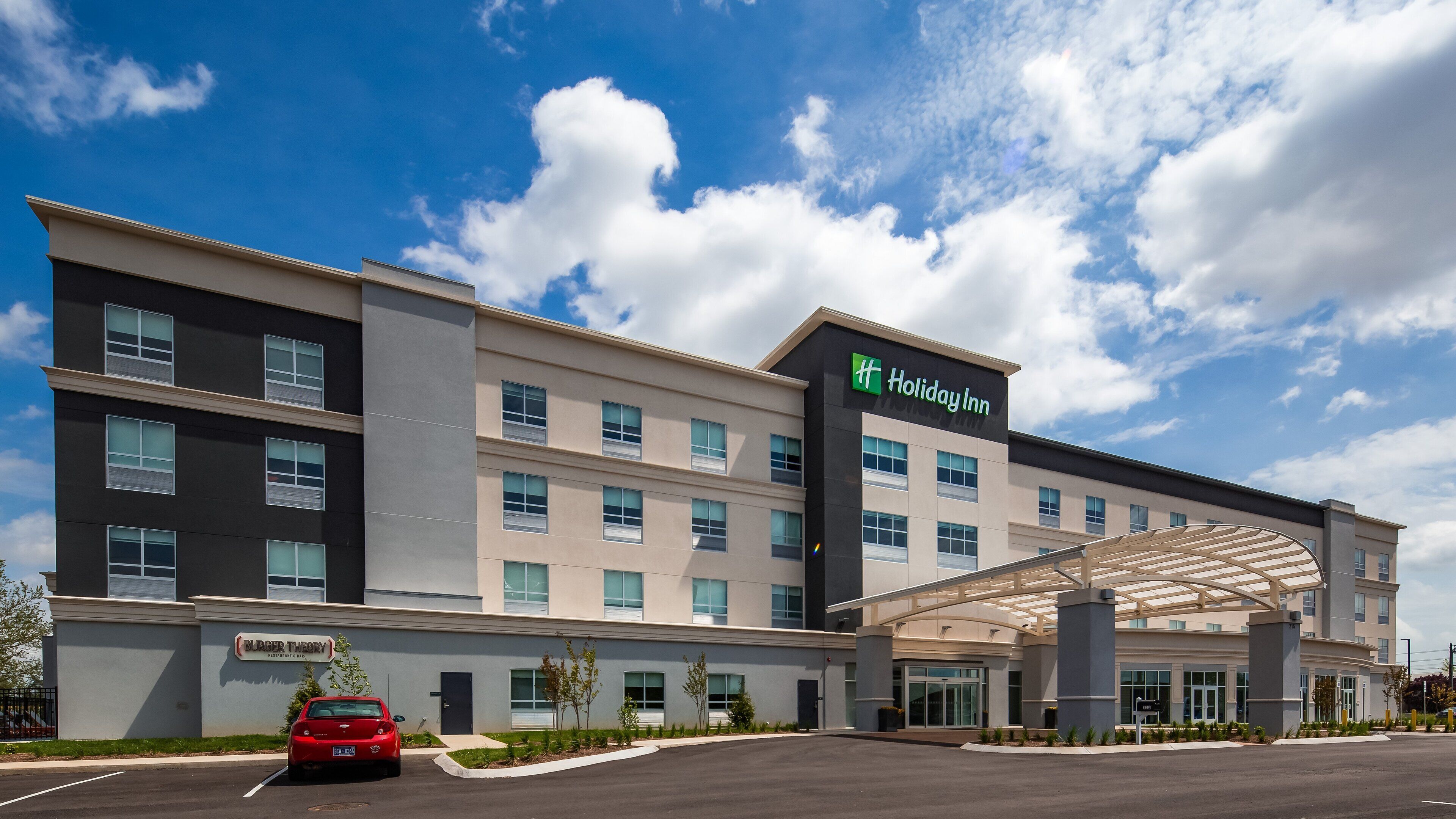 A Holiday Inn hotel with a modern design, featuring a covered entrance and a Burger King across the street.