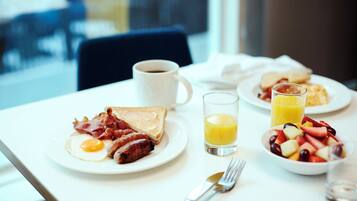 Desayuno con platos de comida, una taza de café y un vaso de zumo de naranja.