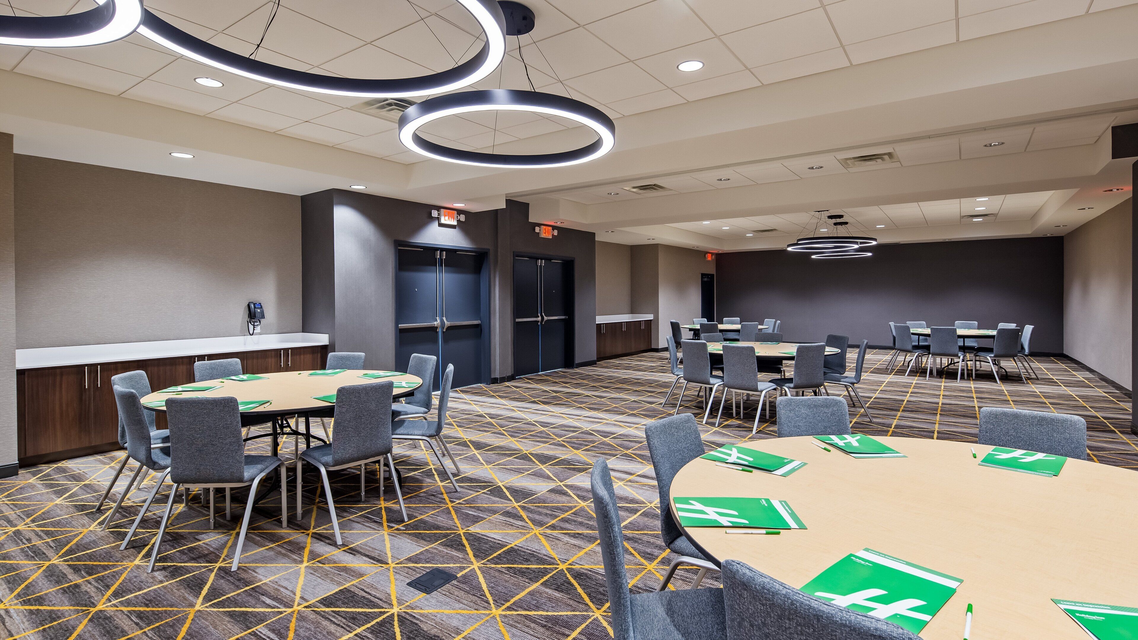 A conference room with a large table, multiple chairs, and a carpeted floor.