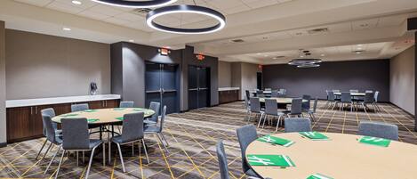 A conference room with a large table, multiple chairs, and a carpeted floor.
