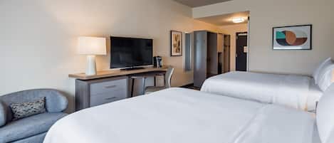 A hotel room with two beds, a desk with a TV, a chair, and a lamp.