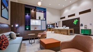 A modern hotel lobby with a reception desk, seating area, and a large digital display. - Holiday Inn Clarksville Northeast by IHG (Clarksville)
