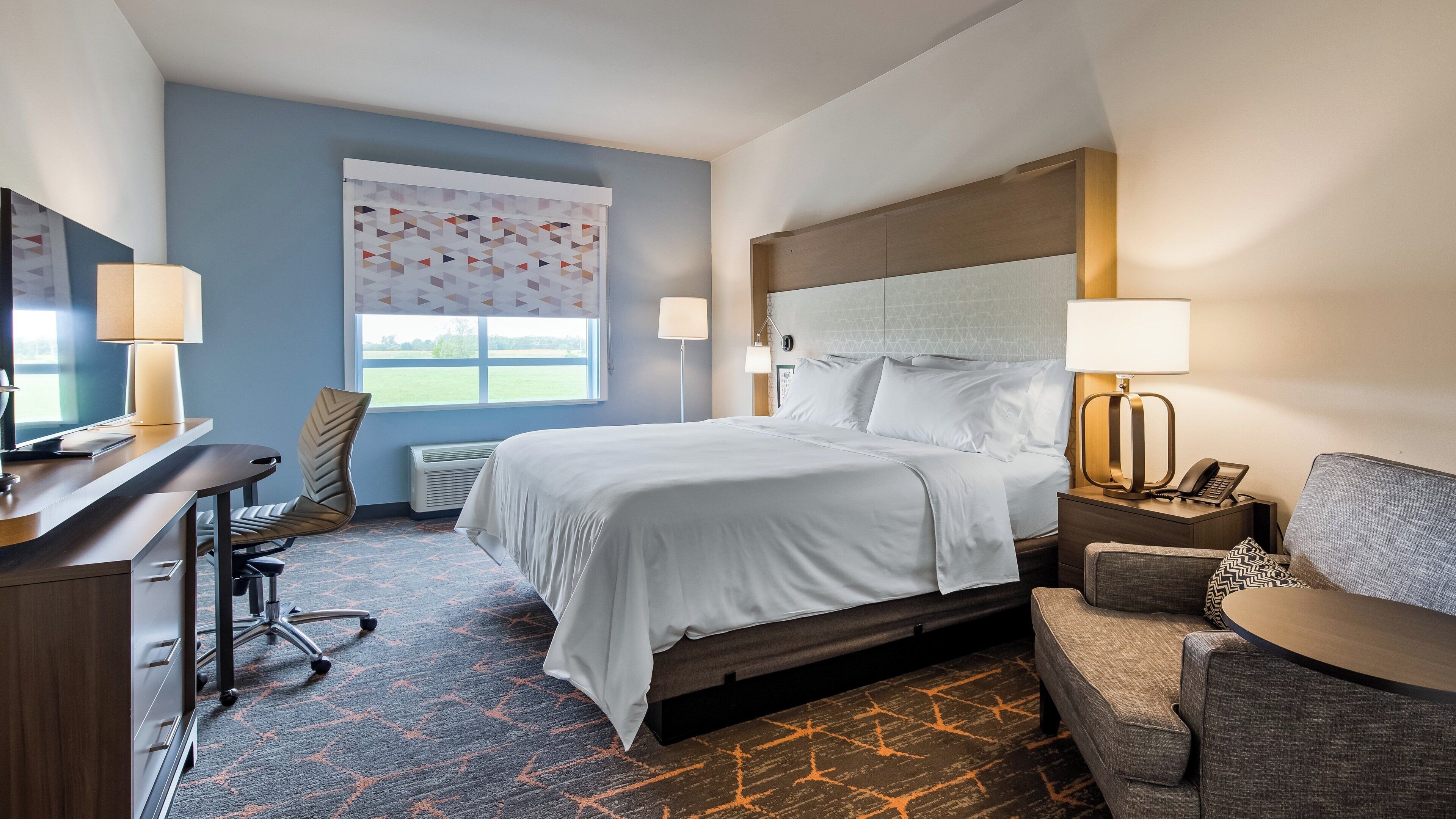 Una habitación de hotel con cama, escritorio, silla, sofá y ventana con vistas.