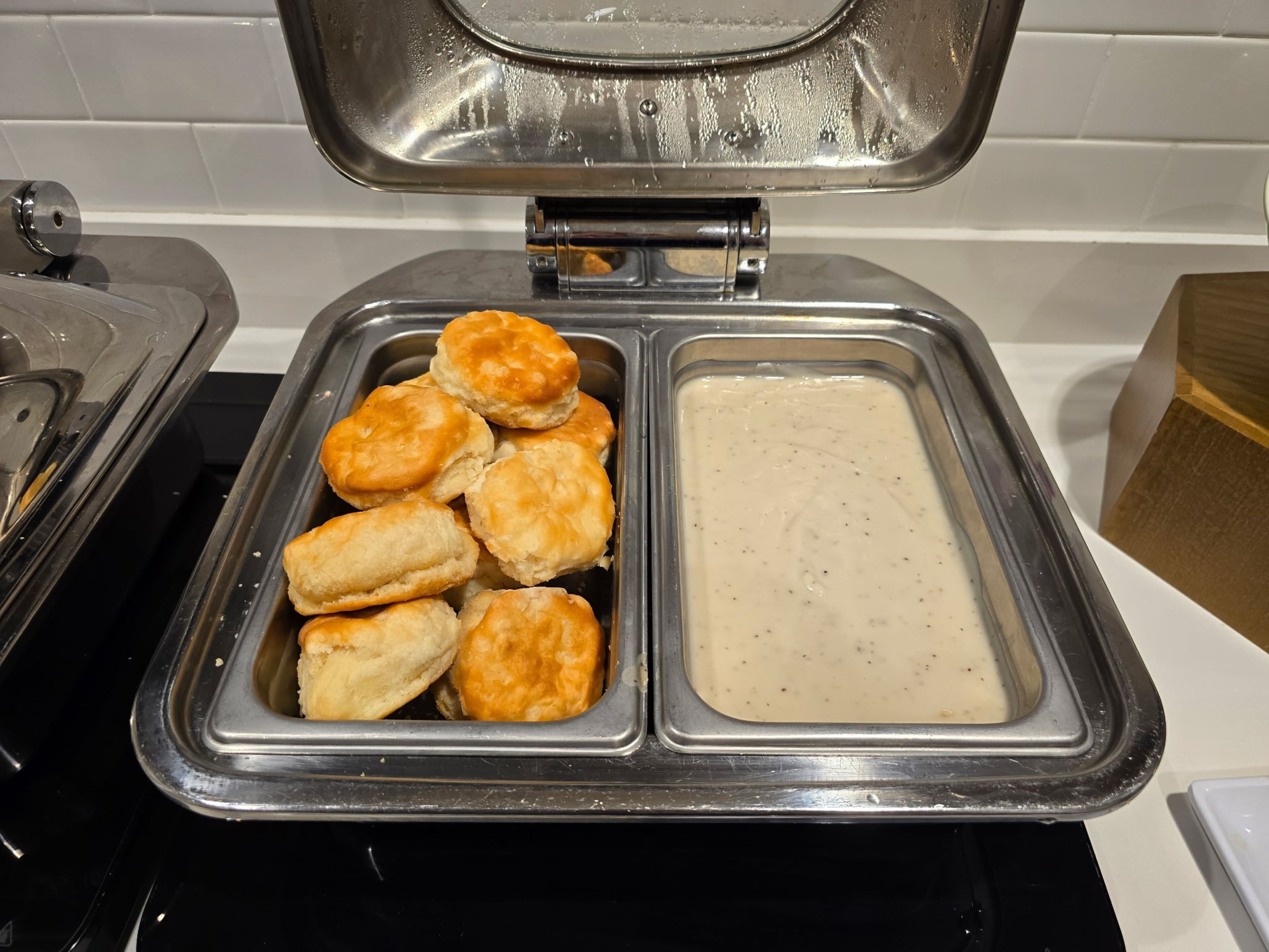 A buffet with a container of biscuits and gravy.