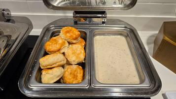A buffet with a container of biscuits and gravy.