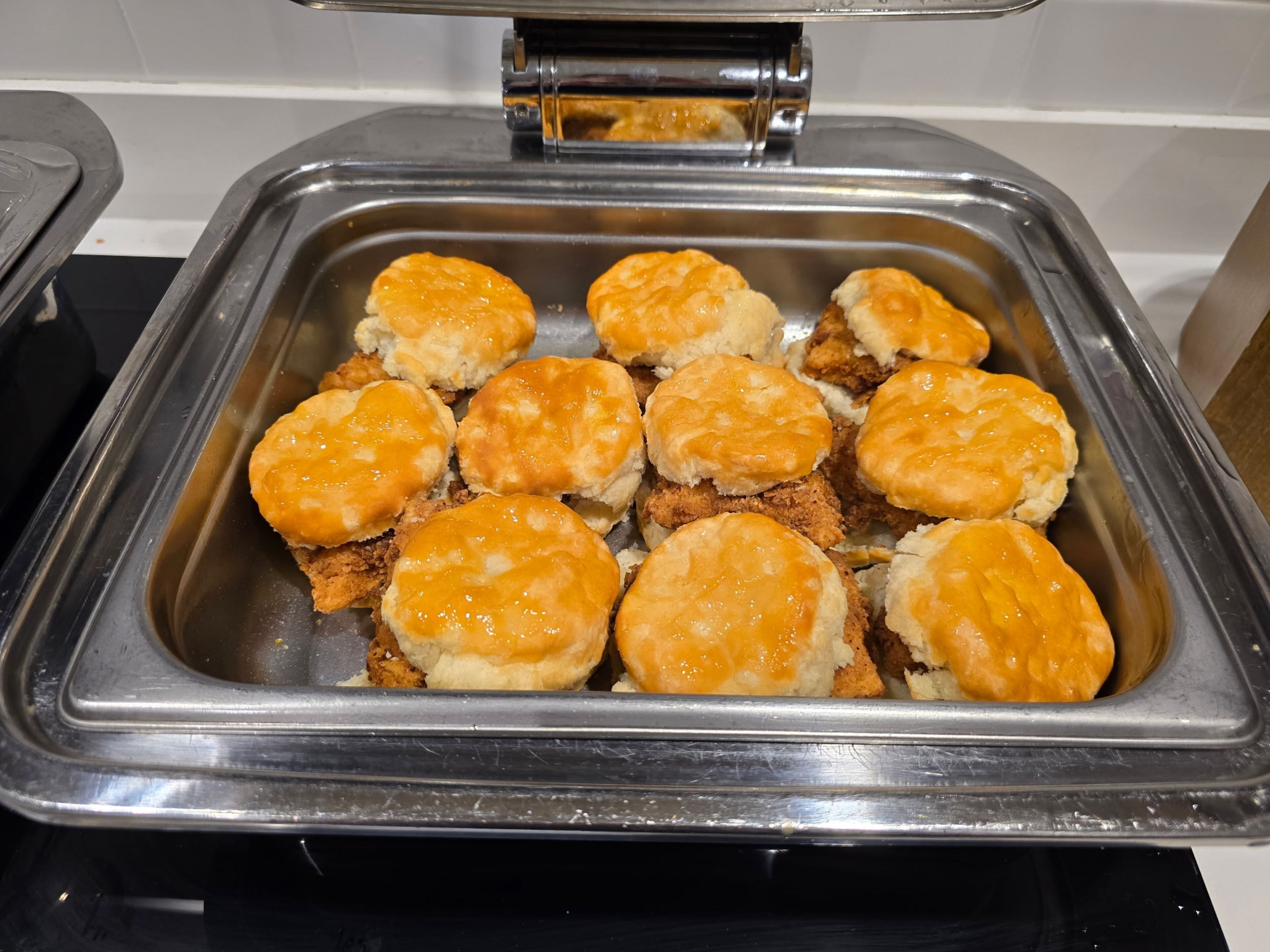 A buffet tray with fried chicken and biscuits.