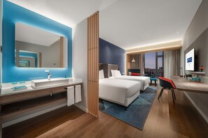 A hotel room with a large mirror, a sink, a bed, a desk, and a view of the city. - Holiday Inn Express Yixing (Wuxi)