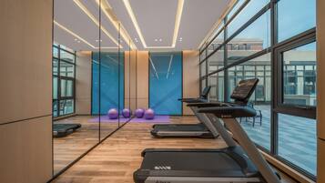 A modern gym with treadmills, exercise balls, and a large window.